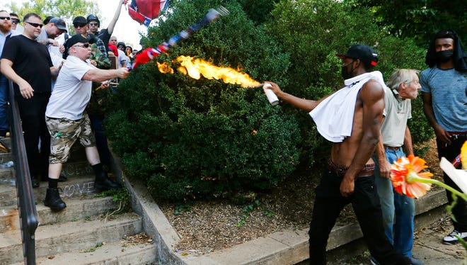 A counter demonstrator uses a lighted spray can against a white nationalist demonstrator at the entrance to Lee Park in Charlottesville, Va., Saturday, Aug. 12, 2017.   Gov. Terry McAuliffe declared a state of emergency and police dressed in riot gear ordered people to disperse after chaotic violent clashes between white nationalists and counter protestors. (AP Photo/Steve Helber)
