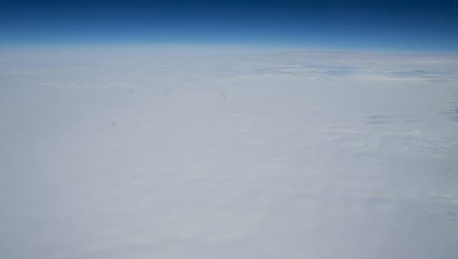 The barren tundra of Greenland almost passes for clouds as a flight passes from Europe to Canada.