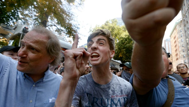 A man wearing a T-shirt bearing the name of President Donald Trump argues with counter-protesters after being hit by a flying plastic bottle of water near a "Free Speech" rally staged by conservative activists in Boston.