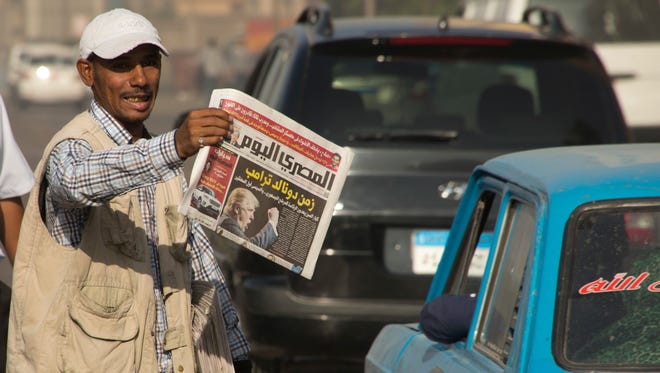 An Egyptian newspaper vendor holds copies of local newspapers fronted with a picture of President-elect Donald Trump with Arabic headline that reads, "Trump era", at a traffic stop, in Cairo, Egypt, Nov. 10, 2016.