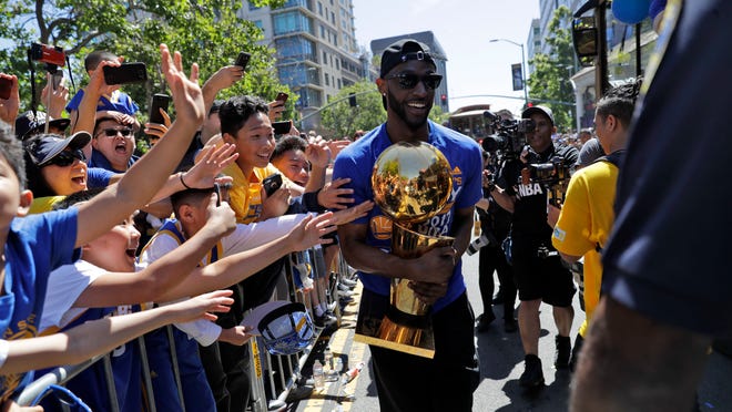 Golden State Warriors' Ian Clark holds the Larry O'Brien trophy during a parade and rally in honor of the Warriors, Thursday, June 15, 2017, in Oakland, Calif., to celebrate the team's NBA basketball championship. (AP Photo/Marcio Jose Sanchez)