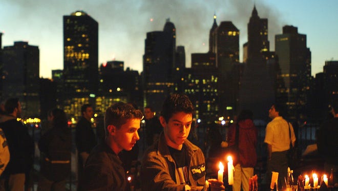 With the skyline of New York City as a backdrop, two young men light candles in remembrance of the victims of the Sept. 11 terrorist attacks on Sept. 14, 2001.