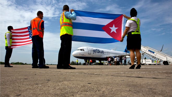 Airport workers receive the JetBlue flight 387 holding the United States and Cuban national flags on the airport tarmac in Santa Clara, Cuba.