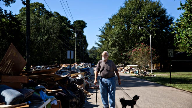 Charles Tripp, 70, of Rome, Georgia, walks his beloved dog, Louie, down what remains of his sister-in-law's street. Charles accompanied his wife down with other family to bring an RV, supplies, and a welcoming embrace and support. "I am supervising, they are labor," he remarks chuckling and pointing to his younger family, " I just had heart surgery." Denham Springs, LA.