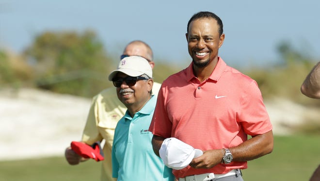 Tiger Woods walks off the 18th green with Pawan Munjal, CEO of Hero MotoCorp, during the Pro-Am at the Hero World Challenge.