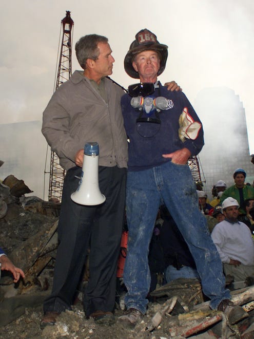 President George W. Bush puts his arms around firefighter Bob Beckwith while standing in front of the World Trade Center site Sept. 14, 2001.