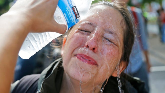 A counter demonstrator gets a splash of water after being hit by pepper spray at the entrance to Lee Park in Charlottesville, Va., Saturday, Aug. 12, 2017. Gov. Terry McAuliffe declared a state of emergency and police dressed in riot gear ordered people to disperse after chaotic violent clashes between white nationalists and counter protestors. (AP Photo/Steve Helber)
