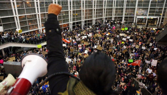 Seattle city councilwoman and socialist activist Kshama Sawant raises a fist over the crowd, as more than 1,000 people gather at Seattle-Tacoma International Airport, to protest President Donald Trump's order that restricts immigration to the U.S., Saturday, Jan. 28, 2017, in Seattle. President Trump signed an executive order Friday that bans legal U.S. residents and visa-holders from seven Muslim-majority nations from entering the U.S. for 90 days and puts an indefinite hold on a program resettling Syrian refugees.