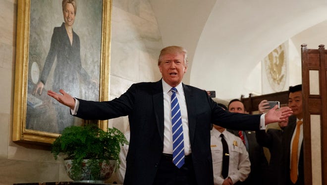 President Trump at the White House in front of a Hillary Clinton portrait.