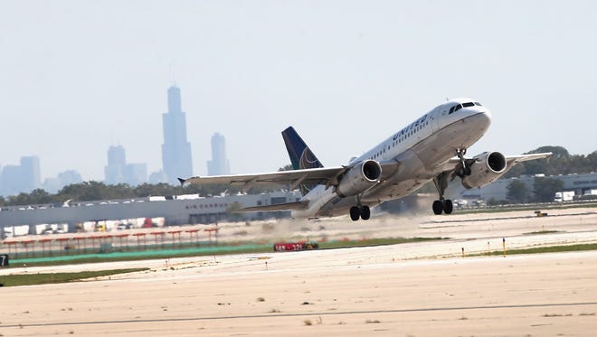 Chicago's skyline is seen as a United Airlines jet takes off from Chicago O'Hare on Sept. 19, 2014. In the distance is the Willis (Sears) Tower that's home to United's official headquarters.