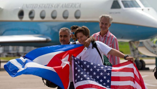 Passengers of JetBlue flight 387 holding a United States, and Cuban national flags, pose for photos in front of the plane transporting U.S. Transportation Secretary Anthony Foxx, at the airport in Santa Clara, Cuba.