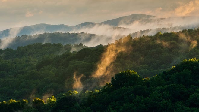 Sunlight hits the morning fog as it lifts from the Shenandoah National Park in Virginia on June 21, 2015.