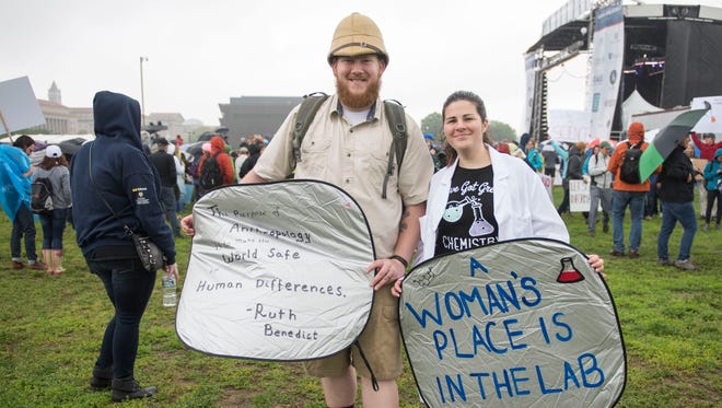 Amy and Anthony Schienschang carry signs at the March for Science in Washington.