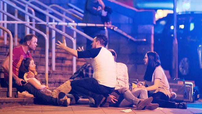 Police and bystanders are seen near the Manchester Arena after reports of an explosion at the Ariana Grande concert, Monday.