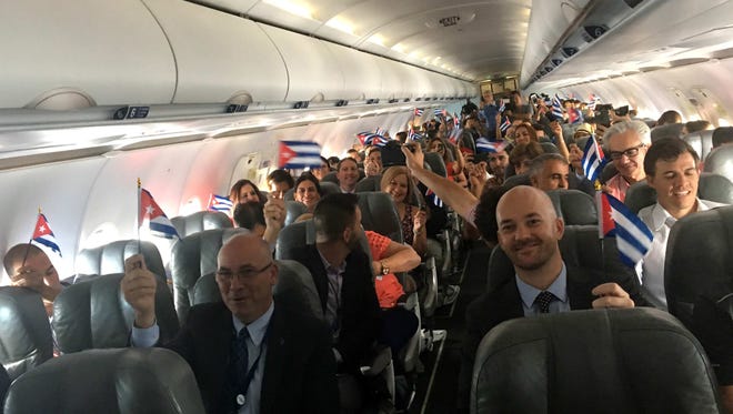 JetBlue flight 387 passengers hold up representations of Cuba's national flag, just before touching down at the airport in Santa Clara, Cuba.