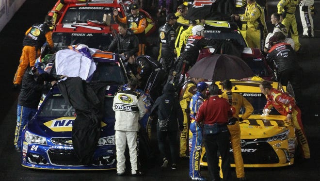 Crews work to cover the cars after rain hit Bristol Motor Speedway halting the race.