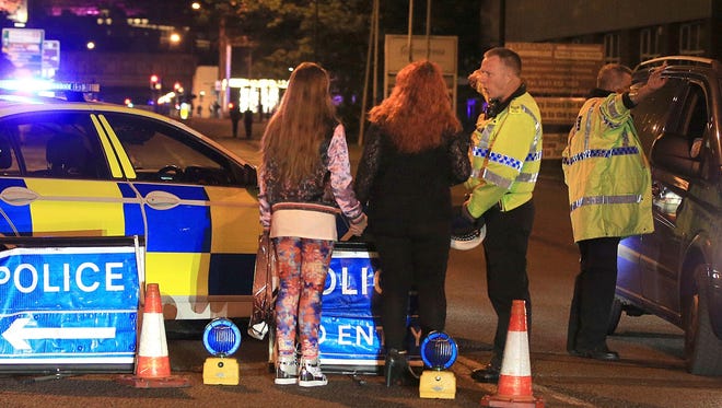 Police talk with bystanders following reports of an explosion at the Manchester Arena.