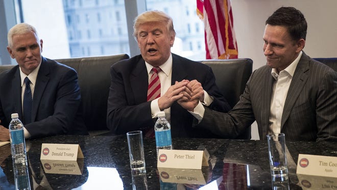 Left to right,Vice President-elect Mike Pence looks on as President-elect Donald Trump shakes the hand of Peter Thiel during a meeting with technology executives at Trump Tower.