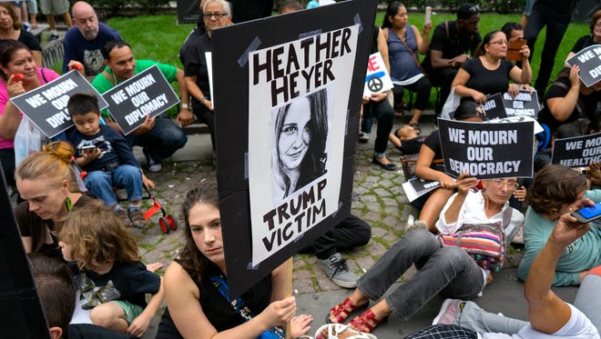 Protestors gather in New York and sit during a moment of silence on Aug. 14, 2017, as they protest President Donald Trump not far from Trump Tower. One person holds a sign referring to Heather Heyer who was killed in Charlottesville, Va., on Saturday, after a car plowed into a crowd.