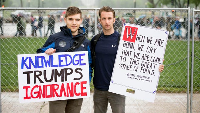 Ryan Powers and Shelby Zemken hold signs during the March for Science rally in Washington, D.C.