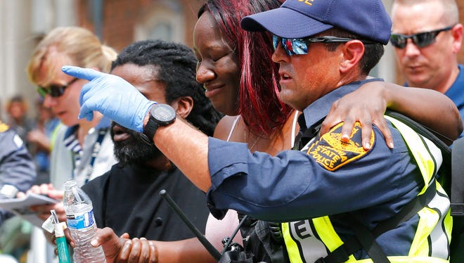 Rescue personnel help an injured woman after a car ran into a large group of protesters after an white nationalist rally in Charlottesville, Va., Saturday, Aug. 12, 2017.  The nationalists were holding the rally to protest plans by the city of Charlottesville to remove a statue of Confederate Gen. Robert E. Lee. There were several hundred protesters marching in a long line when the car drove into a group of them. (AP Photo/Steve Helber)