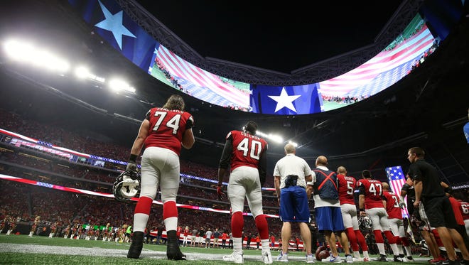 Atlanta Falcons offensive tackle Ty Sambrailo (74), fullback Derrick Coleman (40) and teammates stand during the national anthem before their game against the Green Bay Packers at Mercedes-Benz Stadium.