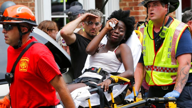Rescue personnel help an injured woman after a car ran into a large group of protesters after an white nationalist rally in Charlottesville, Va., Saturday, Aug. 12, 2017.  The nationalists were holding the rally to protest plans by the city of Charlottesville to remove a statue of Confederate Gen. Robert E. Lee. There were several hundred protesters marching in a long line when the car drove into a group of them.(AP Photo/Steve Helber)