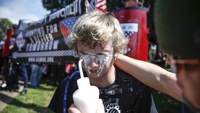 A member of a white nationalist group recovers after being hit by pepper spray by a counter protester on the grounds of Emancipation Park, formerly known as Lee Park, during a 'Unite the Right' rally.