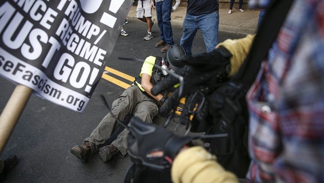 A white nationalist lays on the ground after being knocked unconscious by a counter protester at Emancipation Park, formerly known as Lee Park, during the 'Unite the Right' rally in Charlottesville, Va., on Saturday, August 12, 2017.