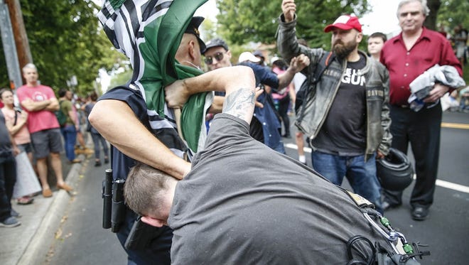 A Charlottesville police officer breaks up a fight on the street in front of Emancipation Park, formerly known as Lee Park, during the 'Unite the Right' rally in Charlottesville, Va., on Saturday, August 12, 2017.
