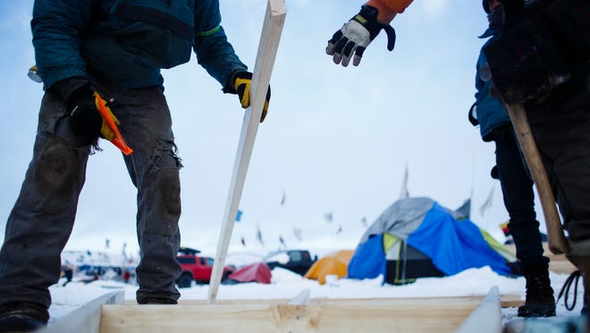 Matt Yerge from Buffalo, NY, right, grabs a stud from Eric Wallace-Scenft of Vermont as they work to build a home in the Oceti Sakowin Camp near the Standing Rock Reservation on Saturday, Dec. 3, 2016 near Cannon Ball. The home is being built a native family who doesn't have a proper winter structure they said.