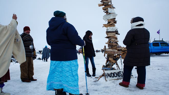Demonstrators look at a a sign post with various waypoints marked on it in the Oceti Sakowin Camp near the Standing Rock Reservation on Saturday, Dec. 3, 2016 near Cannon Ball.