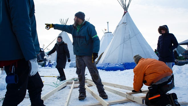 Eric Wallace-Scenft of Vermont, points out a tool hey needs as they work to build a home in the Oceti Sakowin Camp near the Standing Rock Reservation on Saturday, Dec. 3, 2016 near Cannon Ball. The home is being built a native familie who doesn't have a proper winter structure they said.