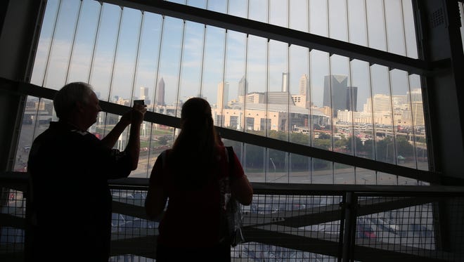 Fans take a photograph of the Atlanta skyline shown through a large window at Mercedes-Benz Stadium.