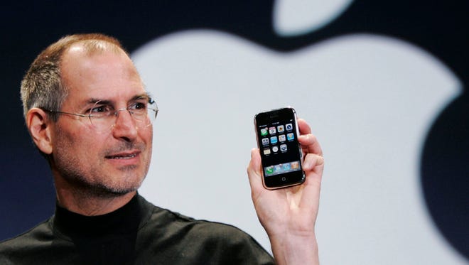 Apple CEO Steve Jobs holds the first generation iPhone at the Macworld Conference in San Francisco on Jan. 9, 2007.