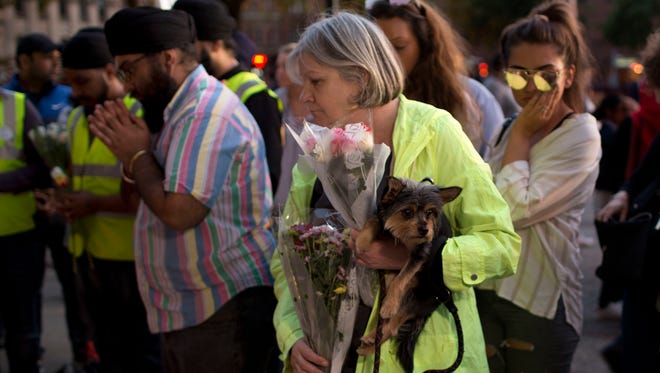 A woman holds her dog before placing flowers after a vigil in Albert Square in Manchester, England, on May 23, 2017.