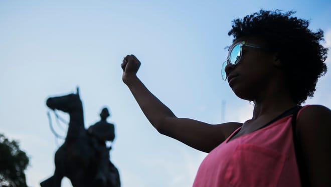 Elechi Egwuekwe, 16, clenches her fist as she stands in front of the Nathan Bedford Forrest statue in Health Sciences Park, in Memphis, at the conclusion of a protest showing support for those who were injured or lost their lives on Saturday in Charlottesville, VA.