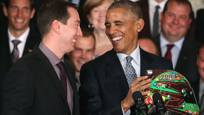 President Barack Obama receives a racing helmet from Sprint Cup champion Kyle Busch during an event in the East Room at the White House.
