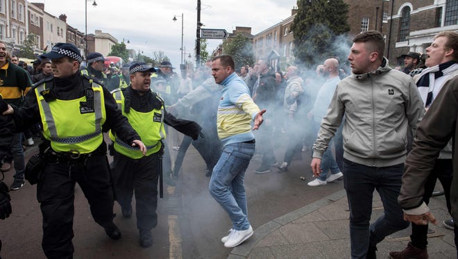 Fans clash as Arsenal supporters are escorted by police past Tottenham fans.