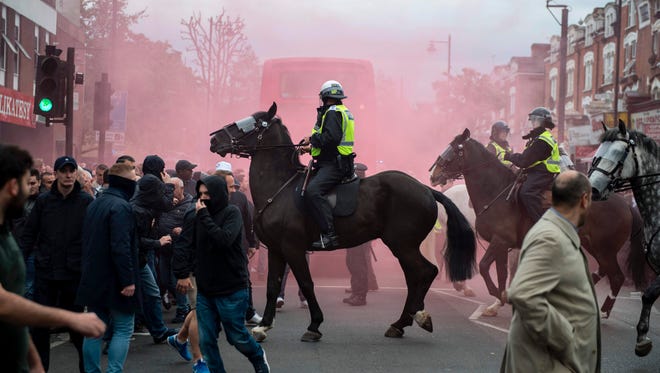 Police intervene in clashes between Arsenal and Tottenham fans.