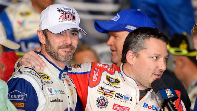 Jimmie Johnson (left) presents Tony Stewart with his helmet in victory lane.
