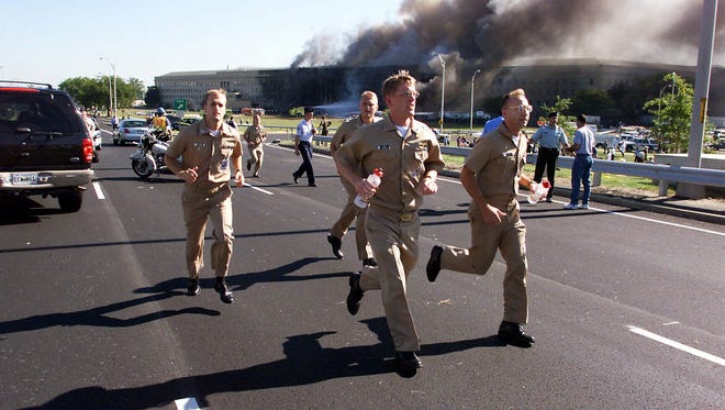 Military personnel flee from the Pentagon after a plane crashed into the building.
