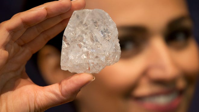 A model poses for photographs holding up the largest gem-quality rough cut diamond discovered in over 100 years, the 1109-Carat Lesedi La Rona at premises of the Sotheby's auction house in London.