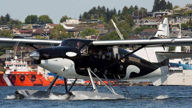 Kenmore Air's newest seaplane, painted like an Orca whale, lands on Lake Union north of downtown Seattle.