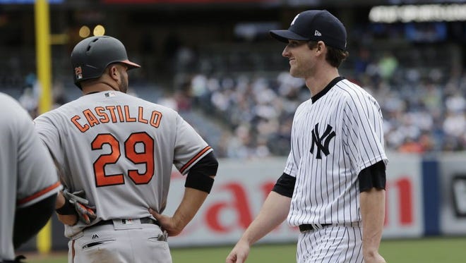 New York Yankees relief pitcher Bryan Mitchell talks with the Baltimore Orioles' Welington Castillo while playing first base.