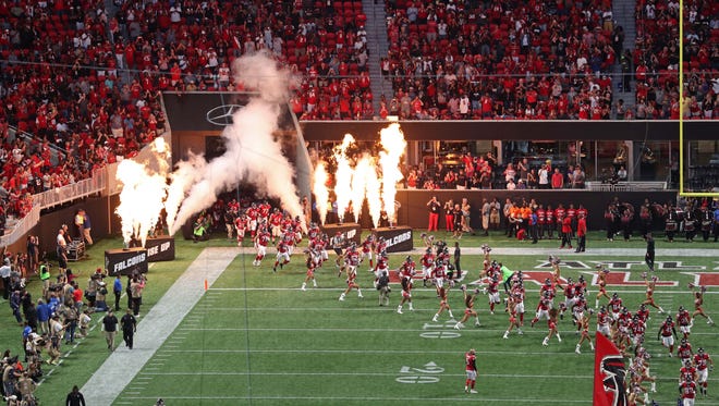 The Atlanta Falcons run onto the field before the first game at new Mercedes-Benz Stadium.