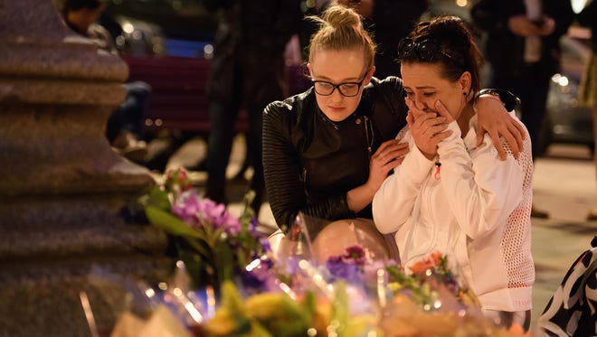 A woman is consoled as she looks at the floral tributes following an evening vigil outside the Town Hall on May 23, 2017, in Manchester, England. An explosion occurred at Manchester Arena as concertgoers were leaving the venue after Ariana Grande had performed. Greater Manchester Police are treating the explosion as a terrorist attack and have confirmed 22 deaths and 59 injured.