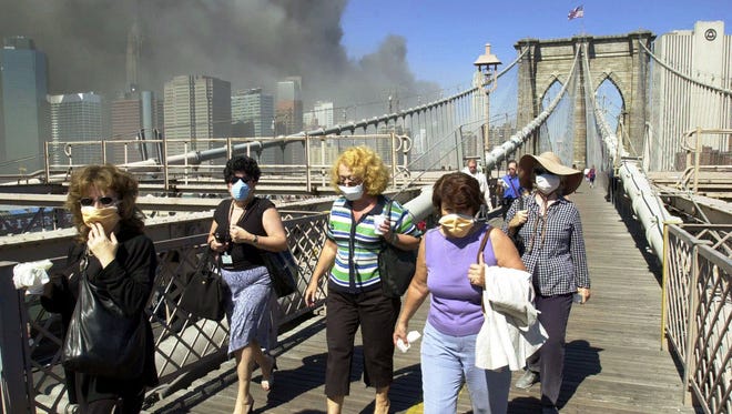 Women wearing dust masks flee across the Brooklyn Bridge from Manhattan to Brooklyn following the collapse of both World Trade Center towers Sept. 11, 2001.