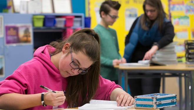 Seventh-grader Kylie Schmitting works on a religion class assignment at Chilton Area Catholic School while teacher Sabrina Holden (right) helps seventh-grader Jack Feider with a question on Feb. 16, 2017, in Chilton, Wis.