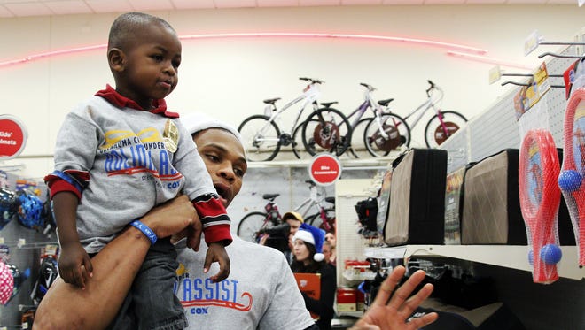 2012: Russell Westbrook carries Keyshaun Sanders, 2, as they shop for toys during the team's annual Holiday Assist in Oklahoma City.
